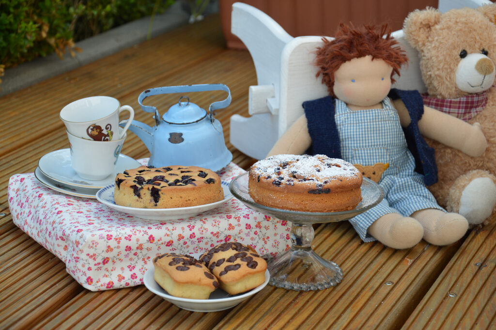 Feste feiern mit Kindern: Kuchen mit Kindergeschirr, Stoffpuppe mit Teddybär